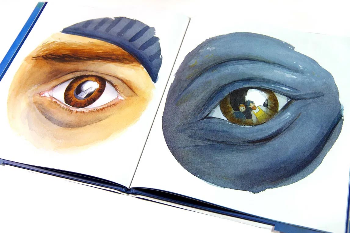 Photograph of interior spread in the picture book 'The Fisherman and the Whale' showing a watercolor closeup image of a human eye on one side and a whale's eye on the facing page.