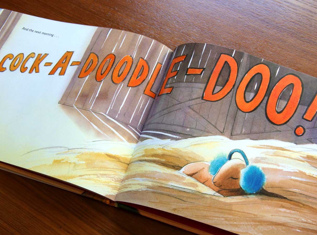 Photograph of open page in the picture book 'A Kid of Their Own' showing the baby goat, Rowdy, sleeping in the hay wearing fuzzy blue earmuffs while enormous orange letters show Clyde the rooster's crow coming in through the door of the barn: 'COCK-A-DOODLE-DOO!'